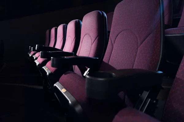 Rangée de sièges rouges dans le cinéma sombre vide — Photo de stock