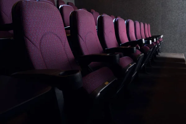 Fileiras de assentos vermelhos no cinema escuro vazio — Fotografia de Stock