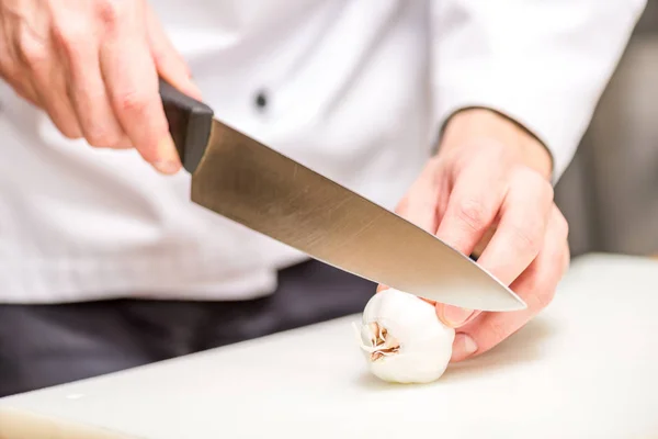 Cropped image of chef cutting garlic — Stock Photo