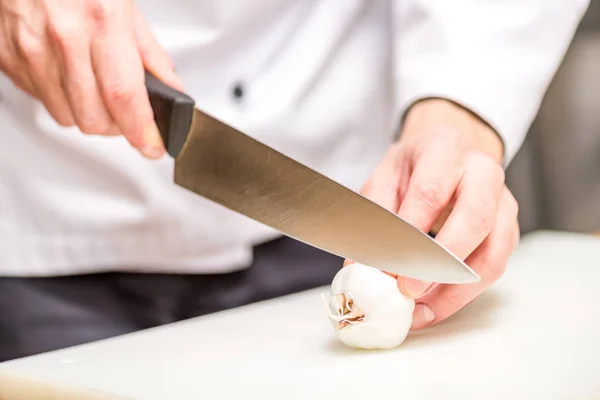 Abgeschnittenes Bild vom Koch, der Knoblauch schneidet — Stockfoto