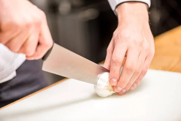 Cropped image of chef cutting garlic — Stock Photo