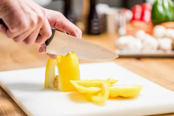 Cropped image of chef cutting yellow bell pepper — Stock Photo