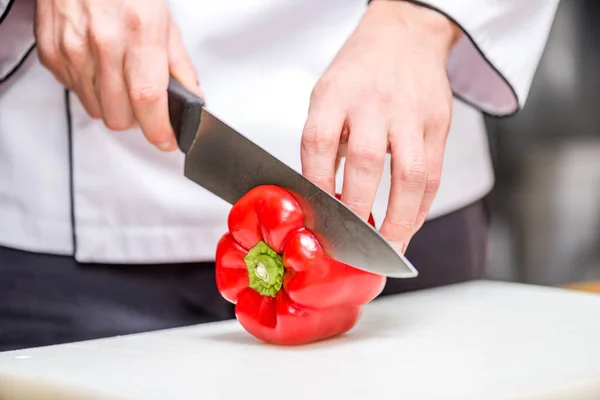 Обрізане зображення шеф-кухаря, що ріже червоний болгарський перець — стокове фото