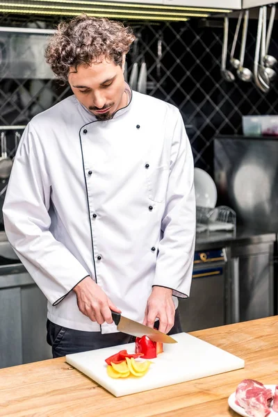 Chef cutting colored bell peppers — Stock Photo