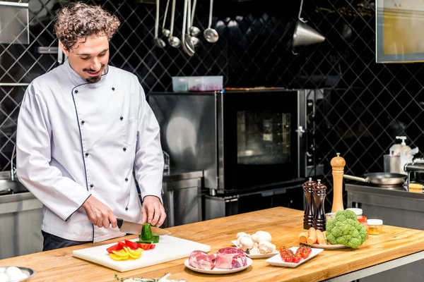 Chef sorrindo cortando pimentas coloridas — Fotografia de Stock