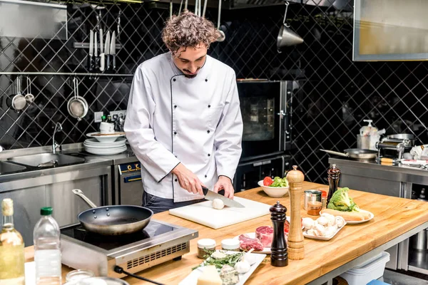 Koch schneidet Pilze in Restaurantküche — Stockfoto