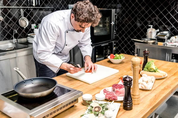 Chef cutting cherry tomatoes at restaurant kitchen — Stock Photo