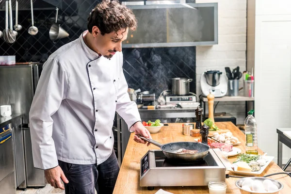 Beau chef frire de la viande dans la cuisine du restaurant — Photo de stock