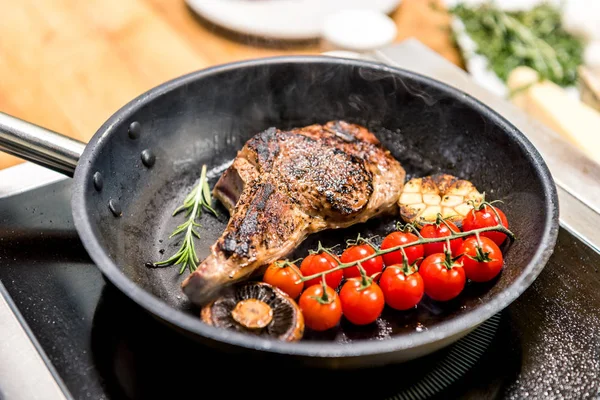 Meat with vegetables on frying pan on electric stove — Stock Photo