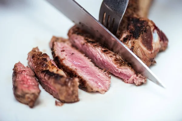 Image recadrée du chef coupant la viande frite au couteau et à la fourchette — Photo de stock