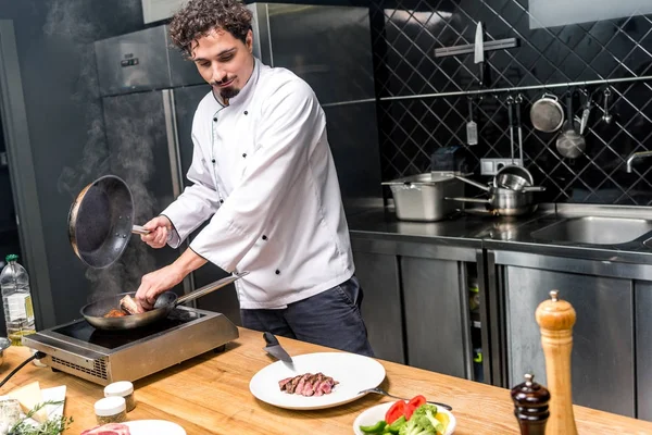 Chef freír carne en la cocina del restaurante - foto de stock
