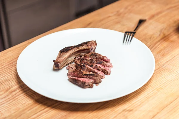 Carne frita en plato blanco sobre mesa de madera - foto de stock