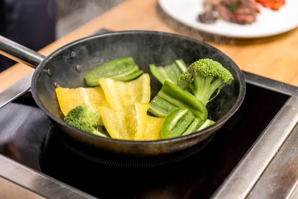 Yellow and green bell peppers with broccoli on frying pan — Stock Photo