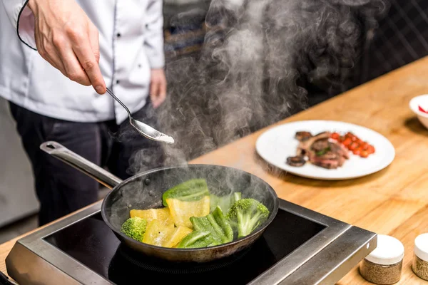 Imagen recortada de chef freír pimientos amarillos y verdes con brócoli - foto de stock