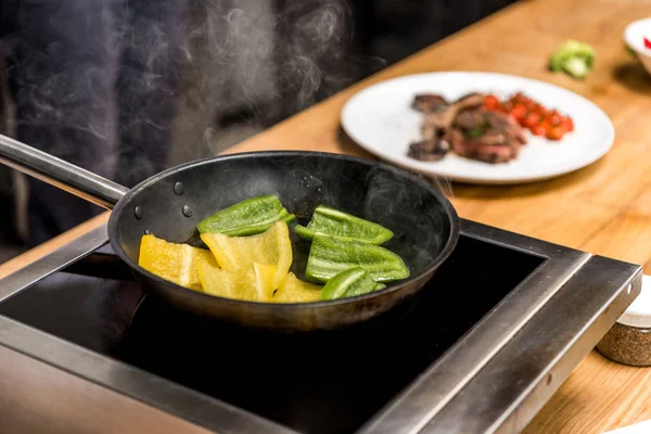 Yellow and green bell peppers on frying pan — Stock Photo