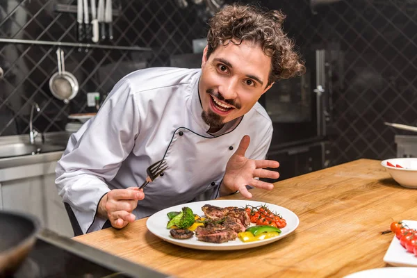 Chef emocionado mostrando verduras cocidas con carne en el plato — Stock Photo