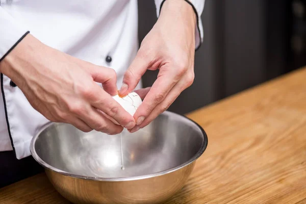 Imagen recortada de chef poniendo huevo en tazón - foto de stock