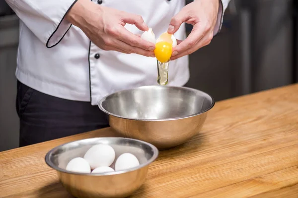 Обрезанное изображение шеф-повара, кладущего яйца в миску — стоковое фото