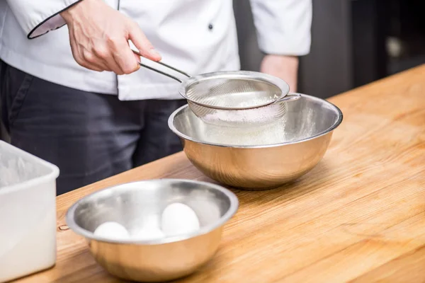 Cropped image of chef holding sieve with flour — Stock Photo