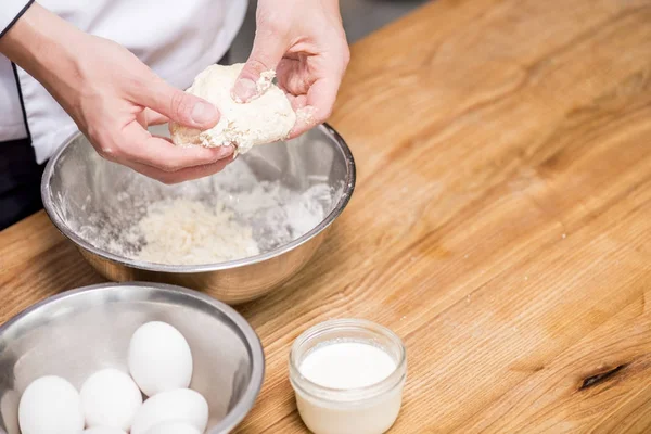 Abgeschnittenes Bild von Koch, der Teig auf Holztisch zubereitet — Stockfoto