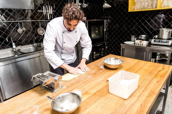 Chef preparing dough for pasta on wooden table — Stock Photo