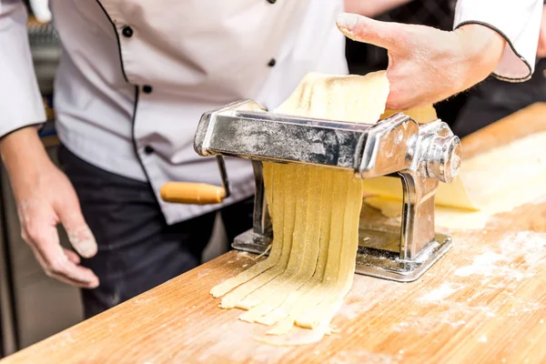 Imagem cortada de chef fazendo macarrão com fabricante de massas — Fotografia de Stock