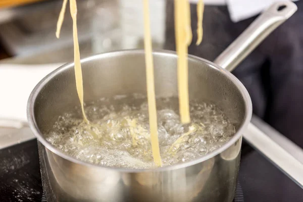 Pasta in boiling water in pot on electric stove — Stock Photo