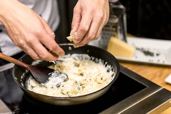 Cropped image of chef adding cheese to pasta — Stock Photo