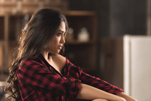 Вид сбоку красивой застенчивой девушки в черной рубашке, отводящей взгляд от дома — стоковое фото