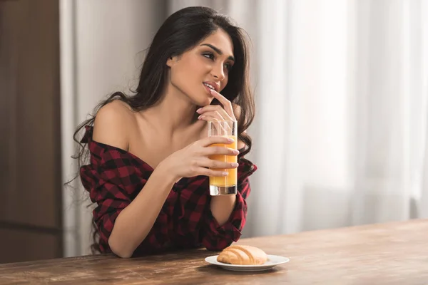 Sexy girl in checkered shirt eating croissant and drinking orange juice for breakfast — Stock Photo