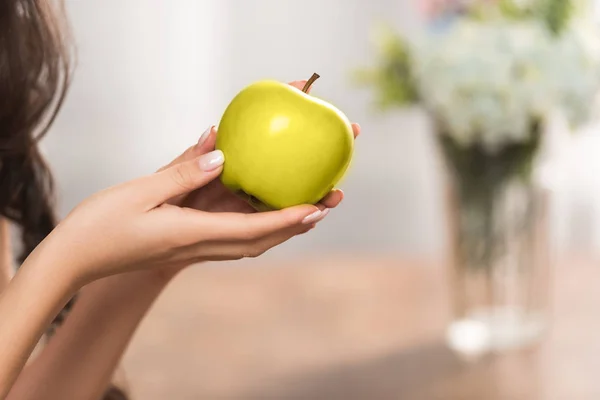 Крупным планом частичный вид девушки, держащей свежее зеленое яблоко — стоковое фото