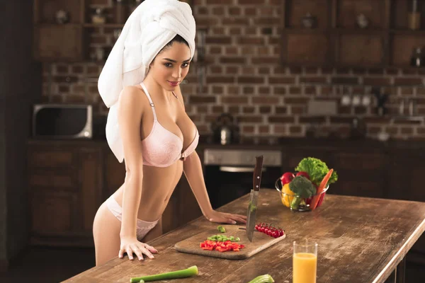 Jovem sexy em lingerie olhando para a câmera enquanto cozinha em casa — Fotografia de Stock