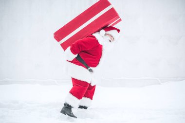 Santa Claus carrying gift box clipart