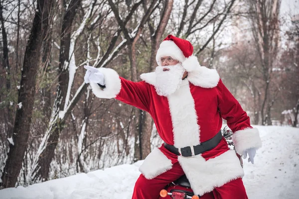 Santa Claus on scooter pointing — Free Stock Photo