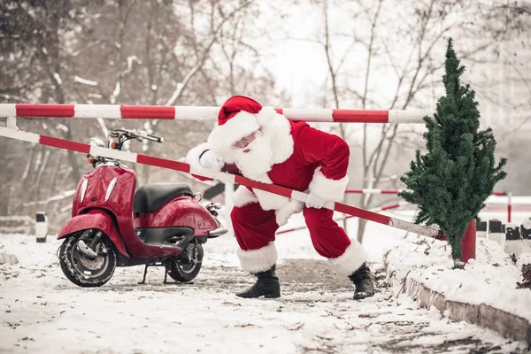 Santa Claus climbing over barrier — Stock Photo, Image