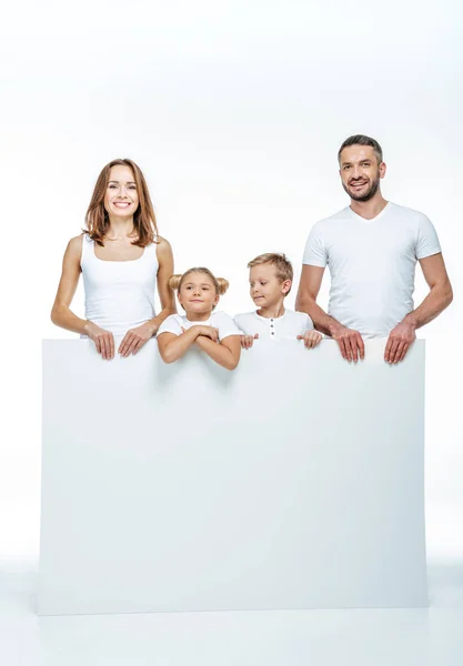 Familia alegre sosteniendo la tarjeta en blanco — Foto de Stock