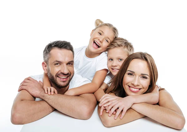 Усміхнена сім'я в білих футболках обіймає — стокове фото