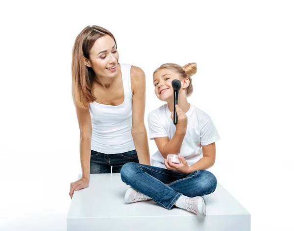 Mother looking at daughter with makeup brush — Stock Photo, Image
