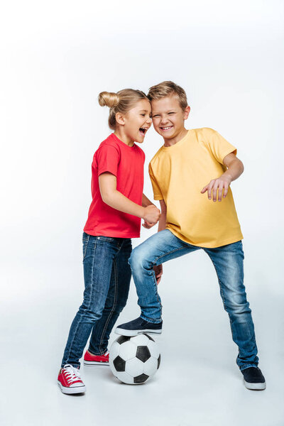 siblings standing with soccer ball