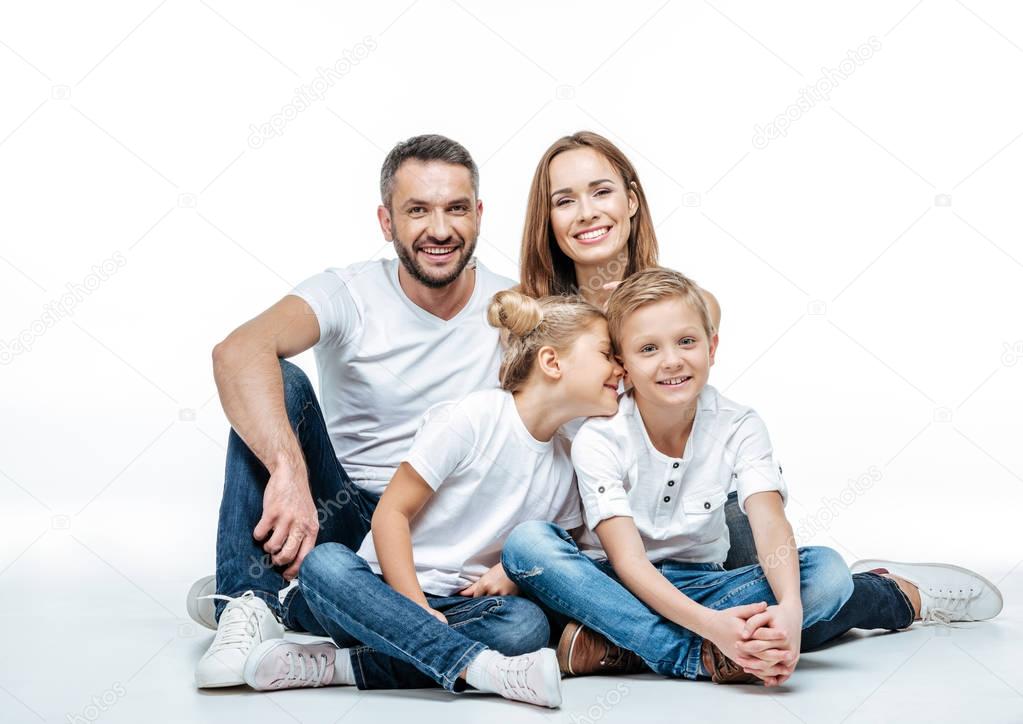 Happy family with two children sitting together and looking at camera isolated on white