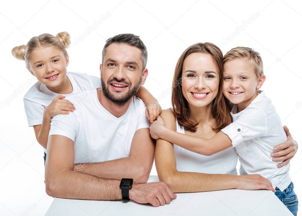 Smiling family in white t-shirts hugging 