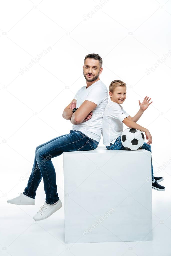 Father and son sitting with soccer ball 