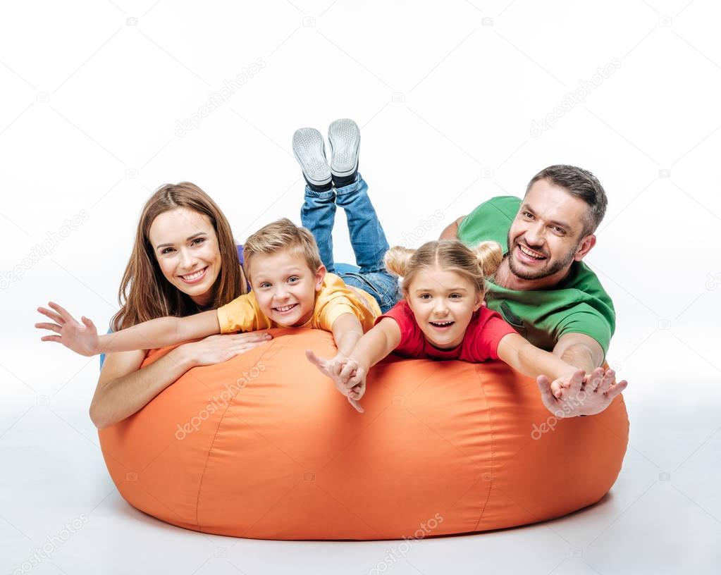Happy family having fun together in sack-chair and looking at camera isolated on white