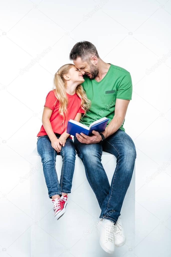 father and daughter sitting with book