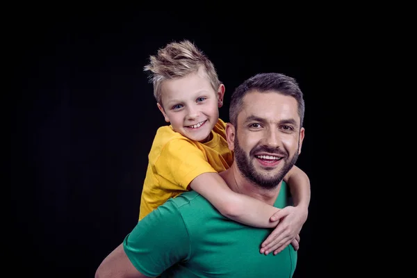 Uśmiechnięty ojciec piggybacking szczęśliwy syn — Zdjęcie stockowe