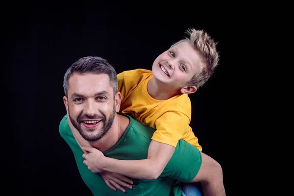 Sorrindo pai piggybacking feliz filho — Fotografia de Stock