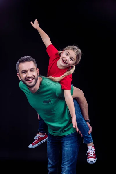 Father piggybacking happy daughter