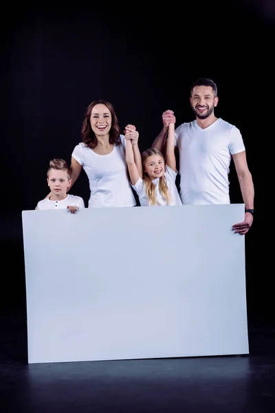 Família de pé com cartão branco em branco — Fotografia de Stock