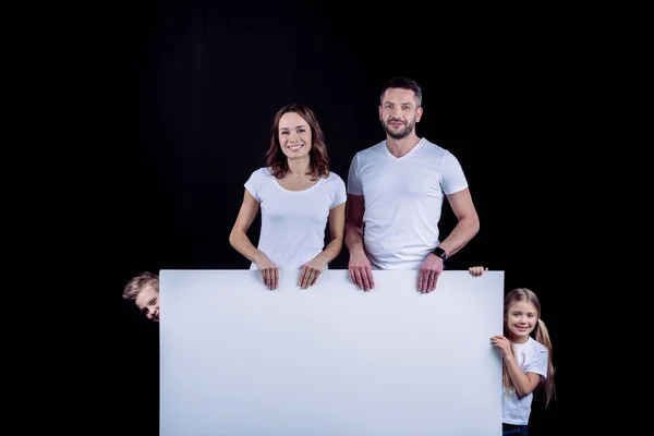 Familia de pie con tarjeta blanca en blanco — Foto de Stock