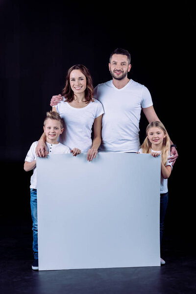 Smiling family holding blank card